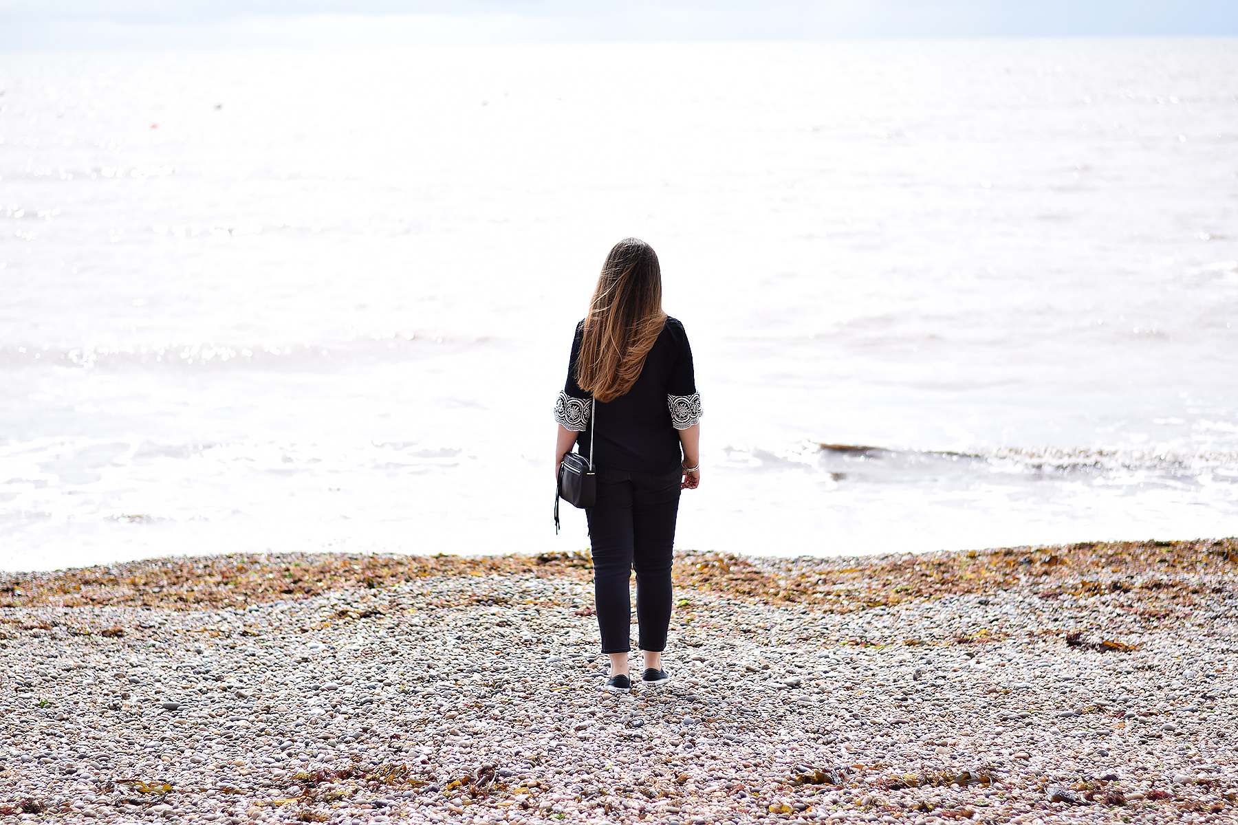 Gemma Jacquard Flower Blog Wearing black embroidered top and looking at the sea