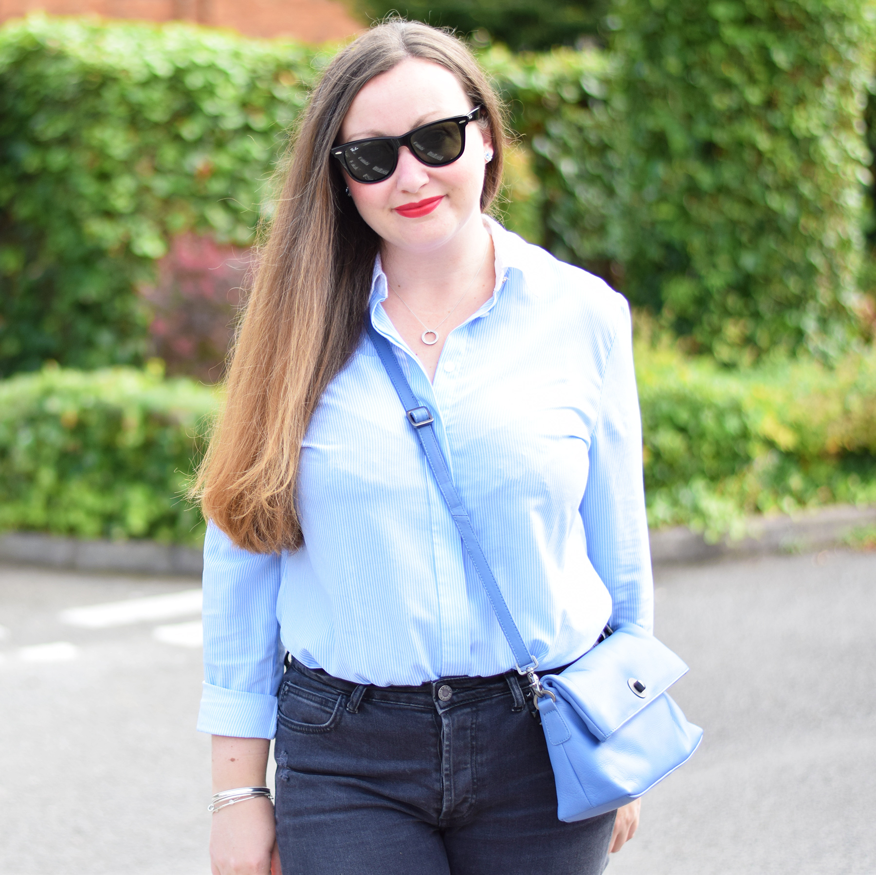 Jacquard Flower Blogger wearing blue striped shirt and black jeans with blue cross body bag