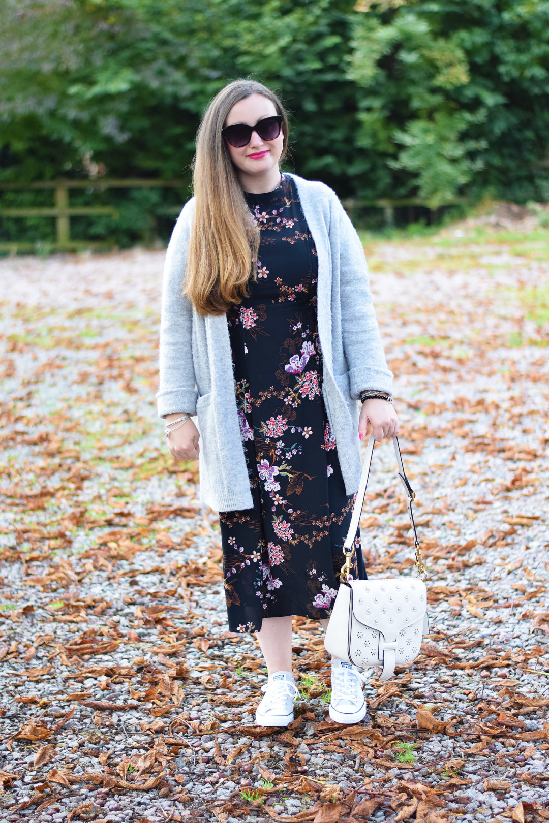 Black floral dress with grey cardigan and sneakers and coach x rodarte bag
