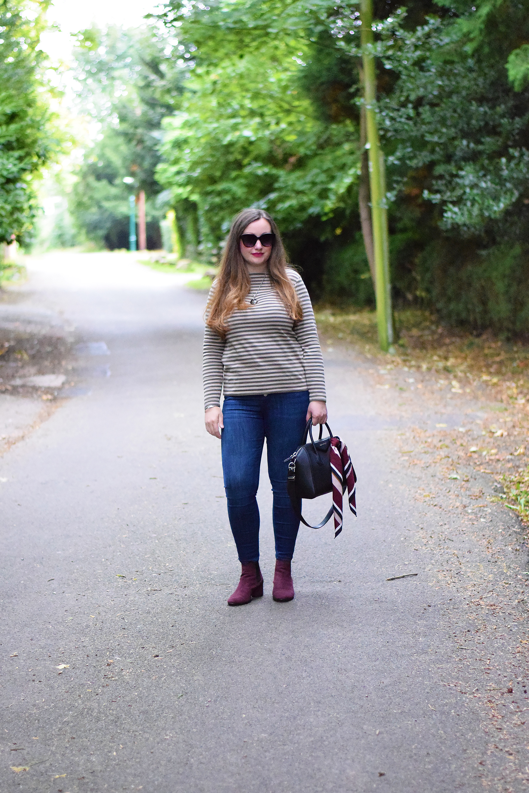 Khaki and grey striped breton top with dark wash skinny jeans and burgundy accessories