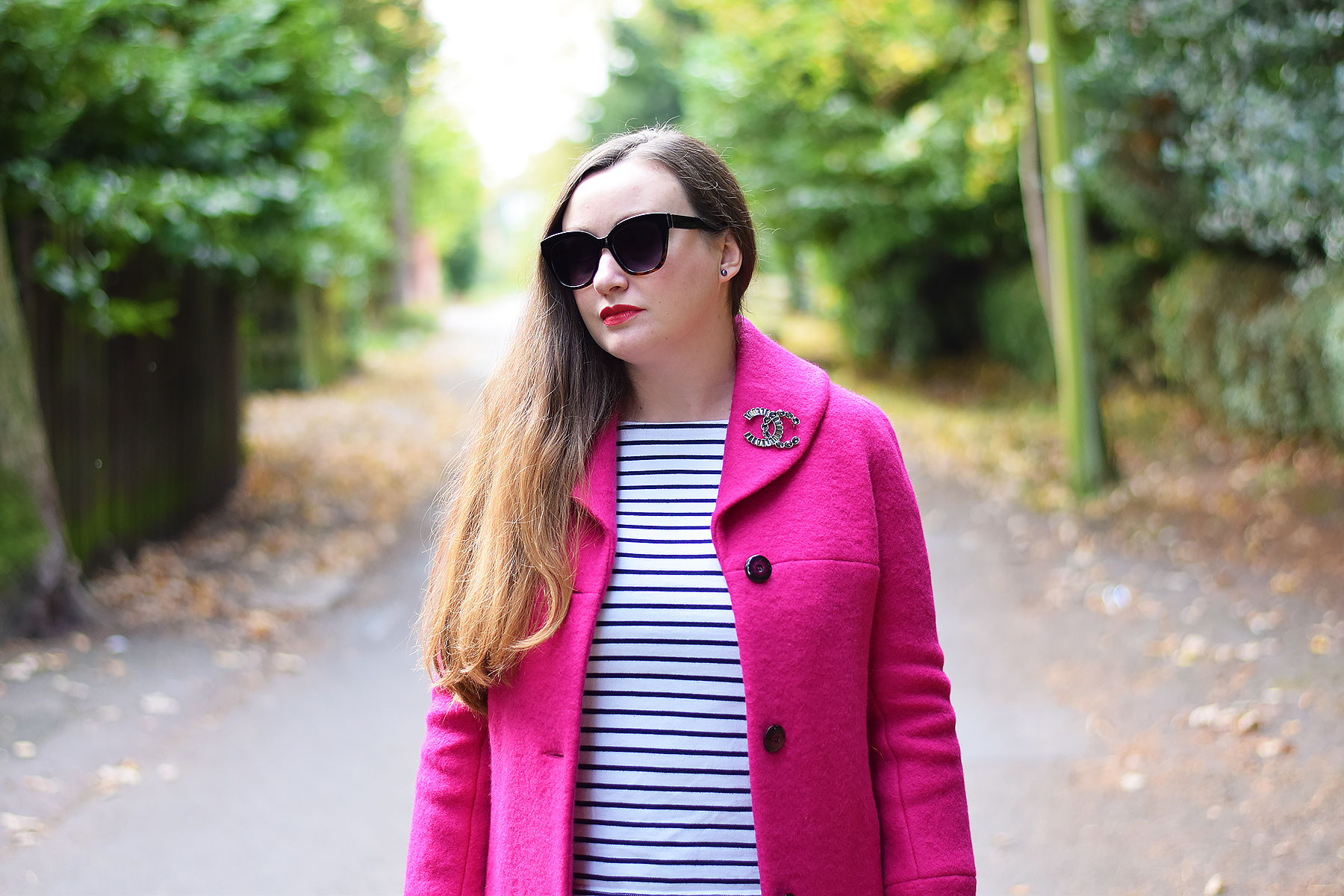 Wearing a chanel cc Brooch on a pink coat with striped top