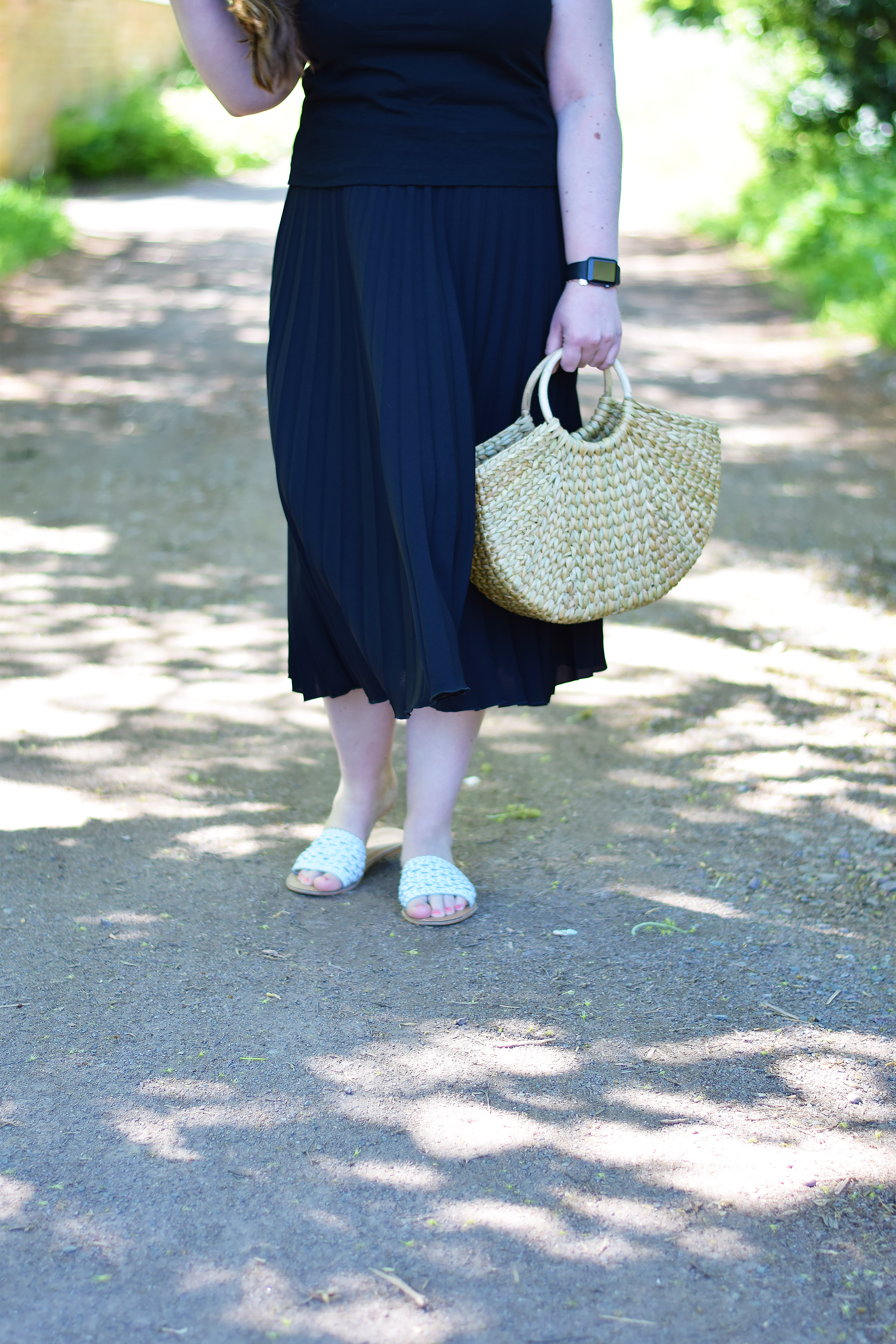 Zara straw bag with rounded handles and black pleated skirt