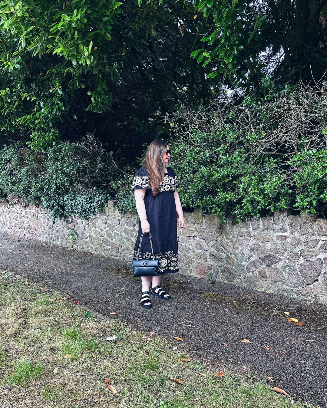 Joanie Alice Dress in Black with embroidery detail. Styled with Dr Martens Gryphon Sandals and Kurt Geiger Kew Bag