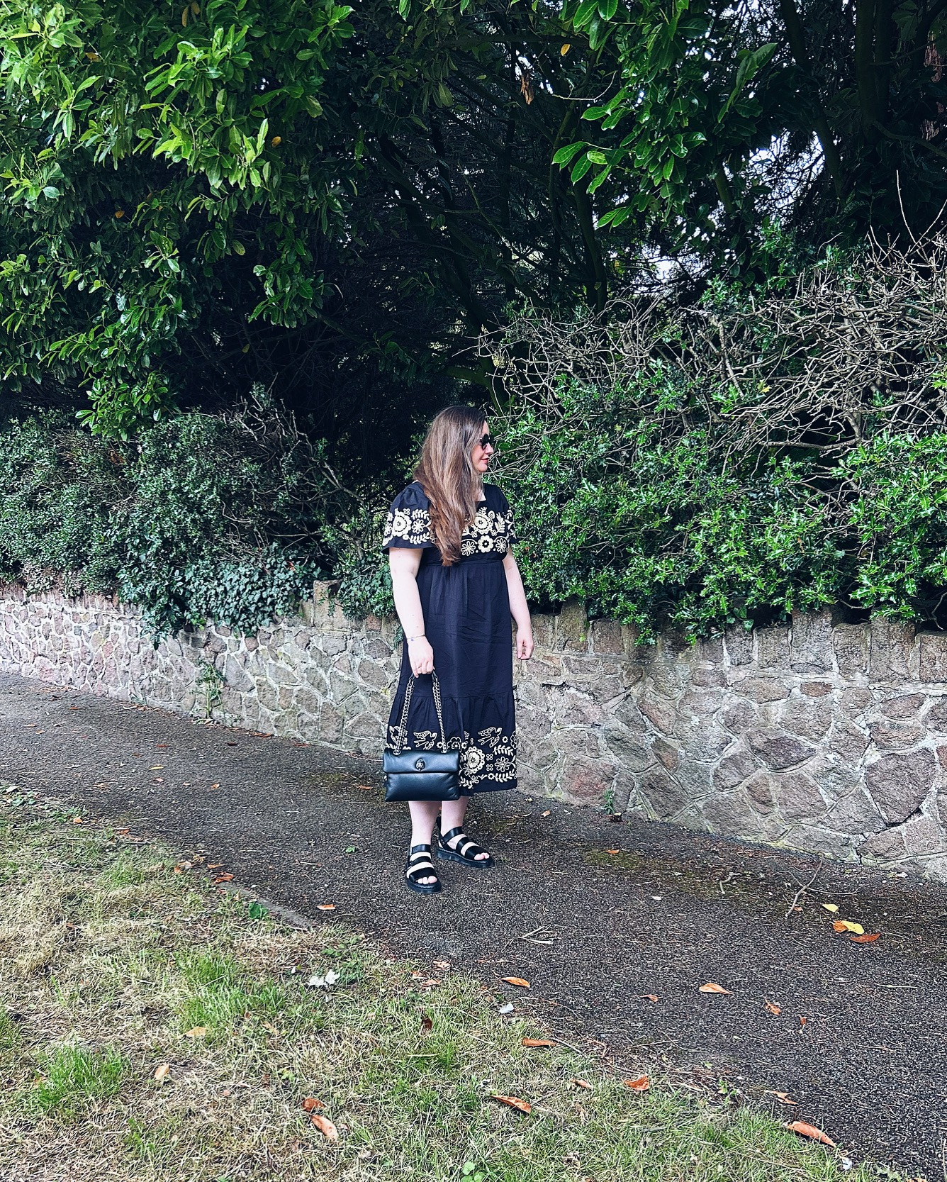 Joanie Alice Dress in Black with embroidery detail. Styled with Dr Martens Gryphon Sandals and Kurt Geiger Kew Bag